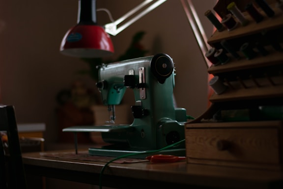 A sleek sewing machine with neon green thread glowing softly against a dark background, symbolizing modern garment craftsmanship.