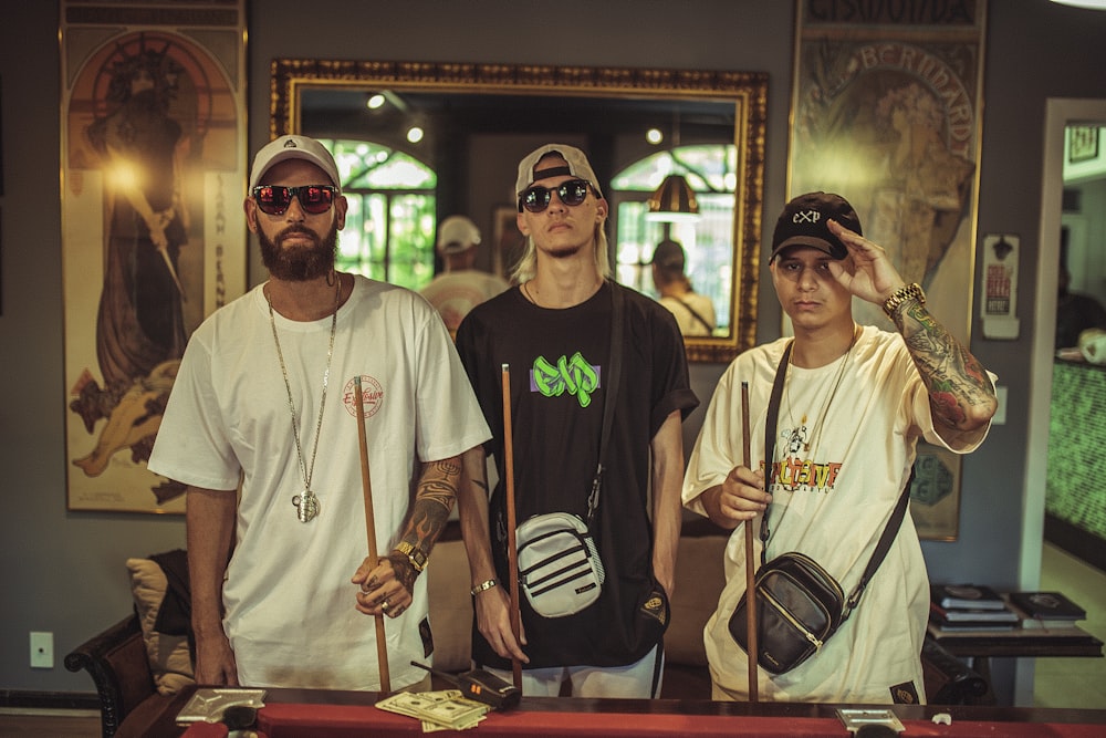 three men standing beside brown pool table