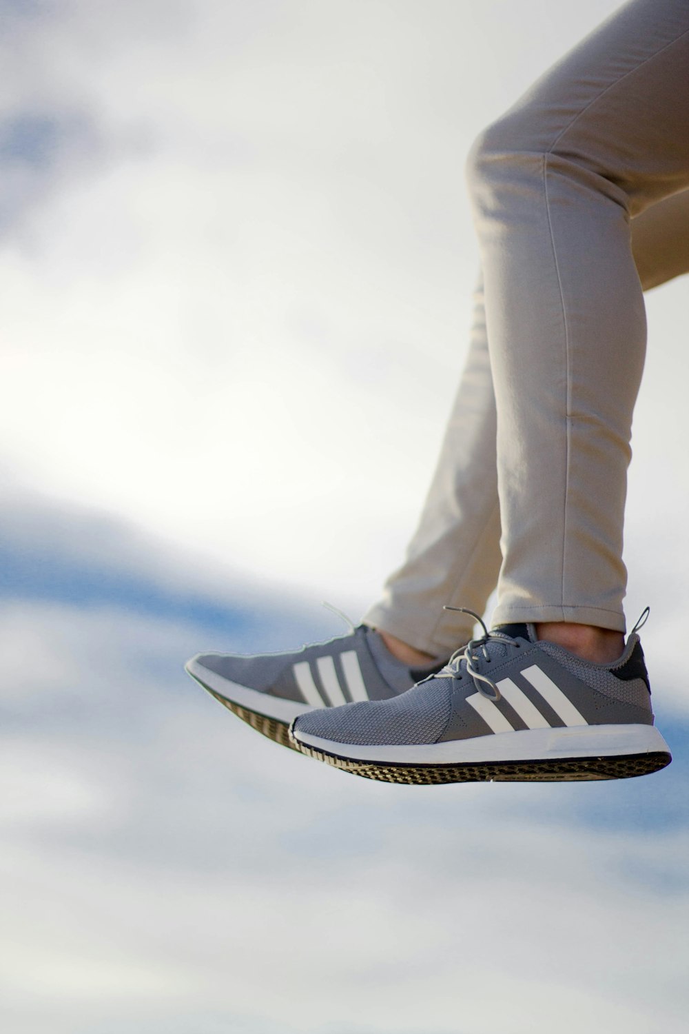 person wearing gray adidas low-top sneakers