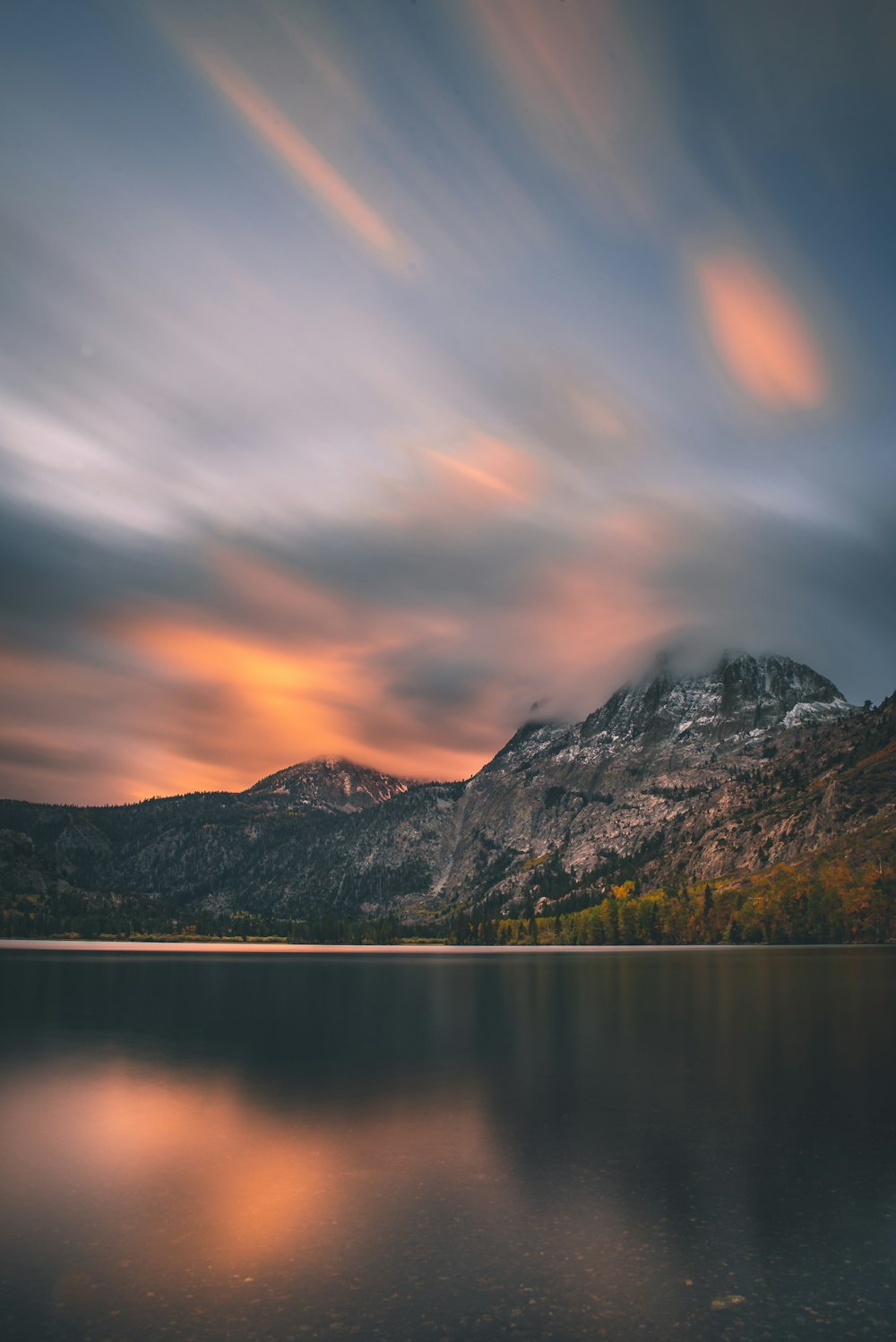 gray mountains beside calm body of water