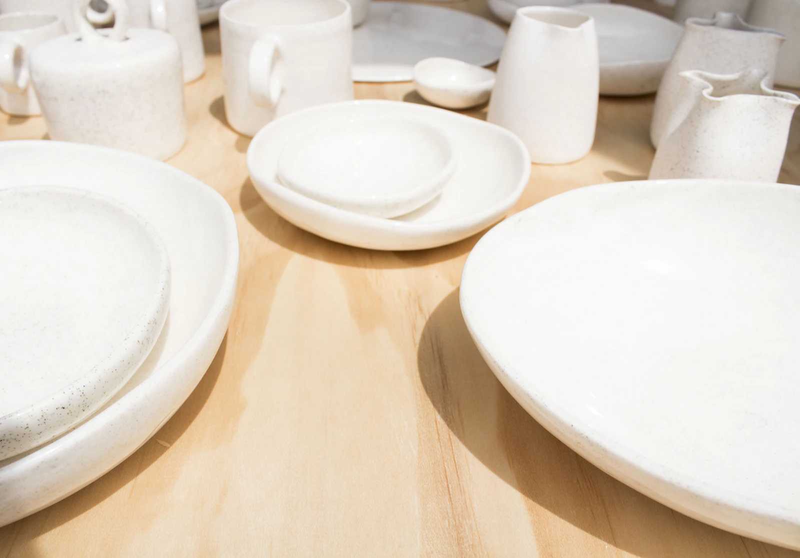 Real ceramic plates bowls and cups displayed in a refined neutral tabletop setting