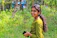 A happy woman using a smartphone outdoors surrounded by greenery.