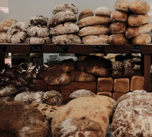 Freshly baked artisanal breads stacked neatly on wooden shelves.