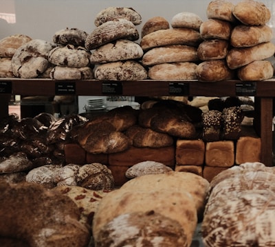 A variety of rustic breads displayed on wooden shelves.