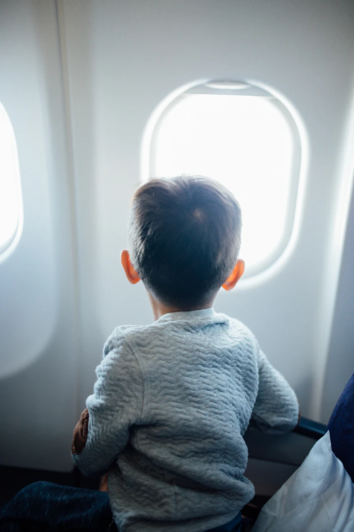 Enfant assis pr&egrave;s du hublot dans un avion