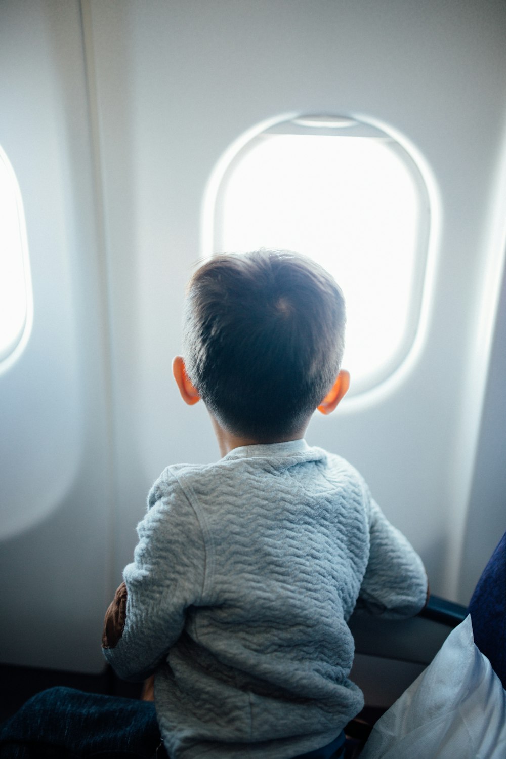 boy sitting on plane seat while viewing window