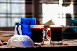 A warm living room scene with a mug and tumbler from the indigo vista collection, both glowing softly.