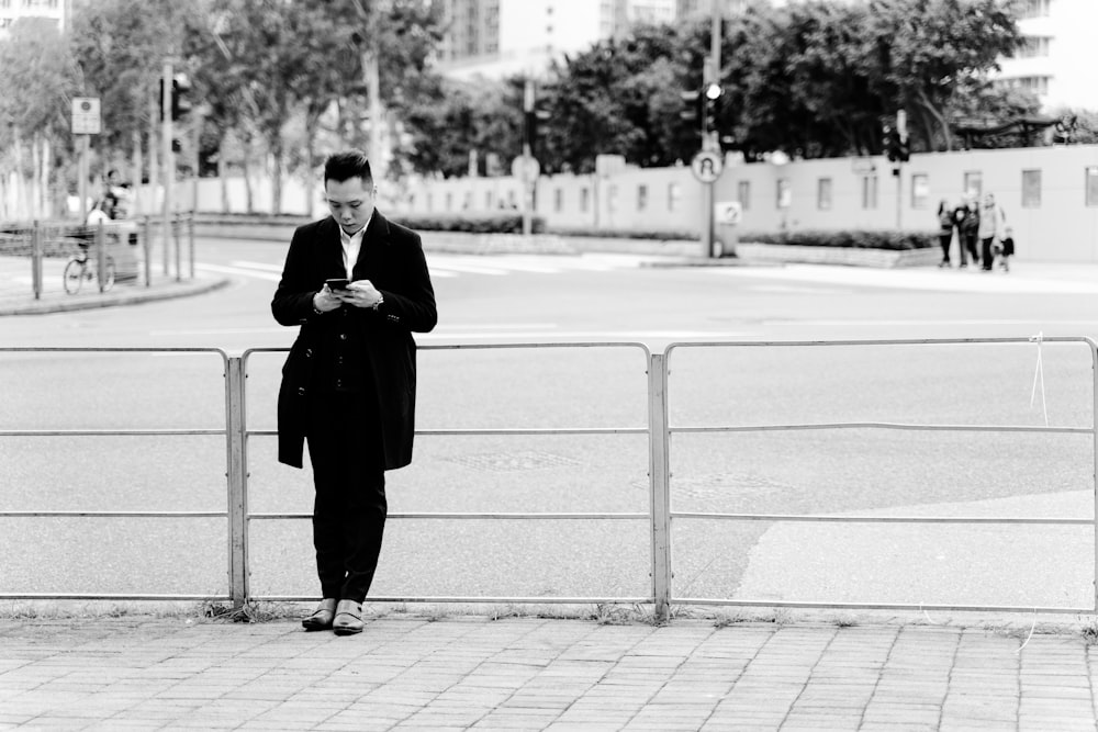 gray scale photo of man leaning on railings