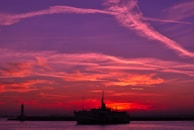 A vibrant sunset over the water with a boat silhouette.