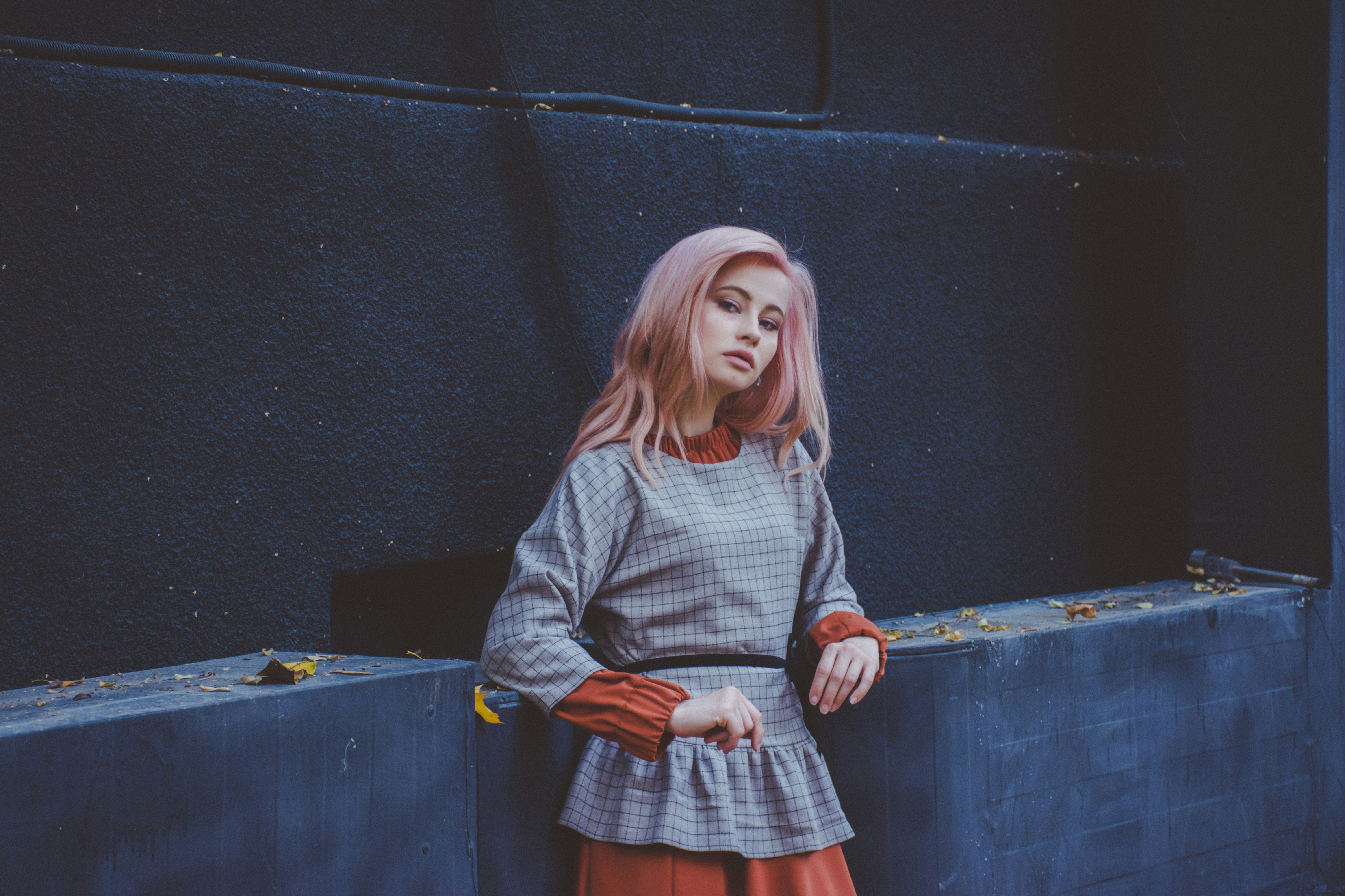 Woman in grey shirt leaning on wall