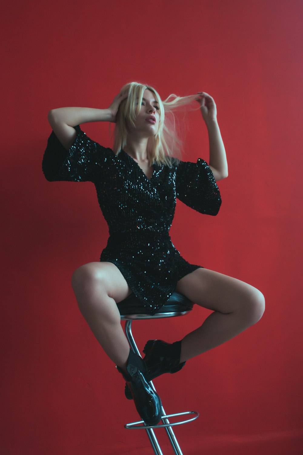 woman sitting on bar stool beside red wall