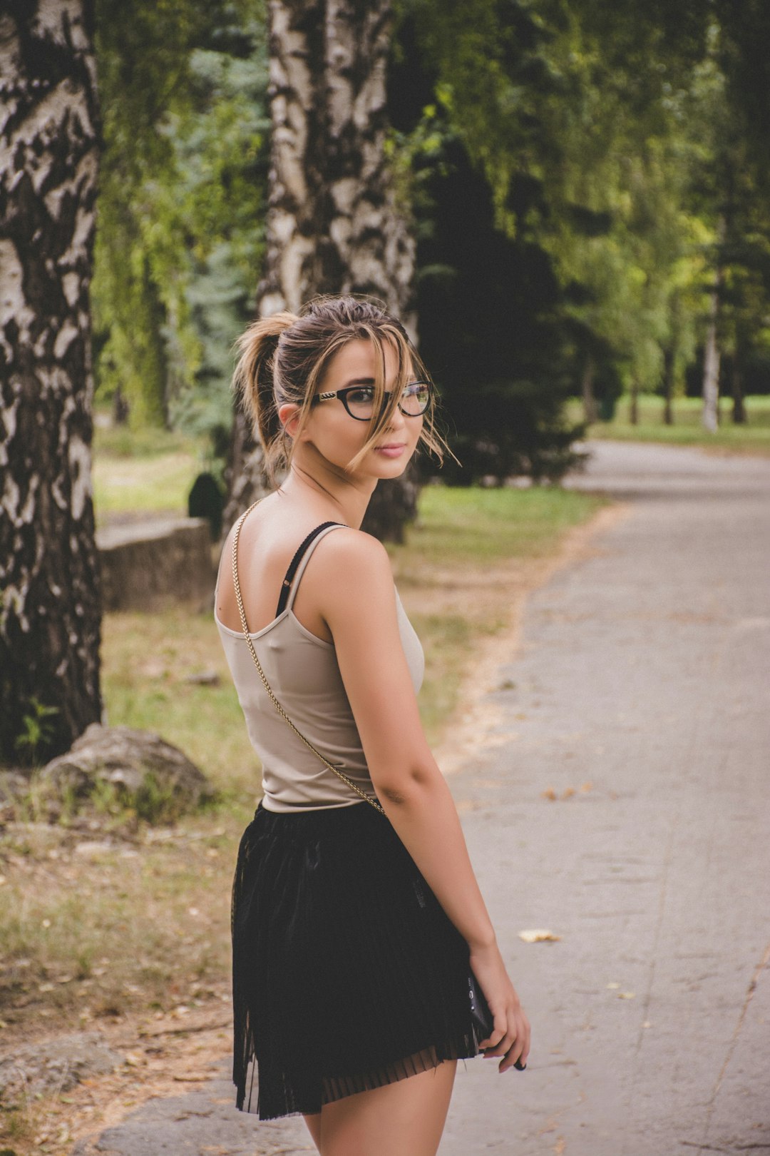 woman standing on pavement near trees