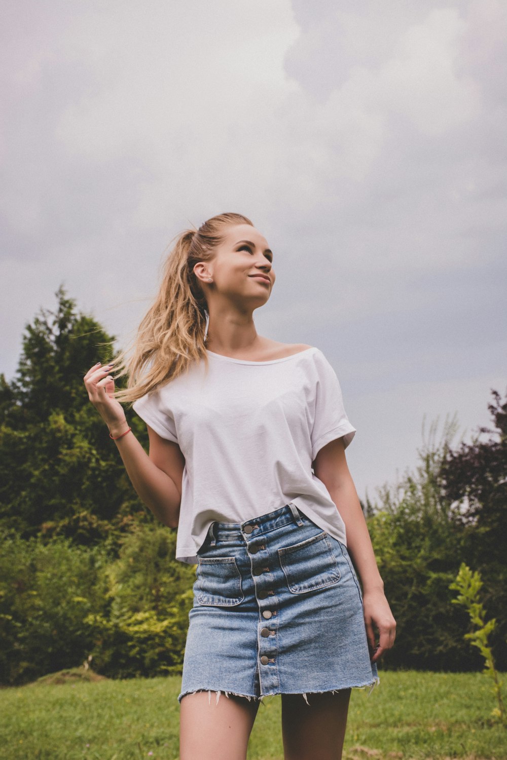 woman in white blouse and denim skirt standing outside and smiling