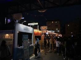 Colorful street festival with people enjoying music and local food stalls.