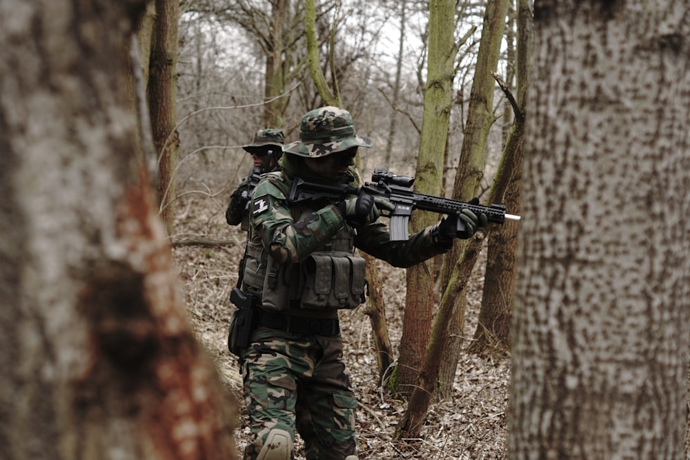 Soldado sosteniendo un rifle de asalto en el bosque