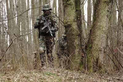 man holding rifle near the tre military teams background