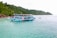 A smiling tourist enjoying a boat tour near Komodo Island with clear blue waters.
