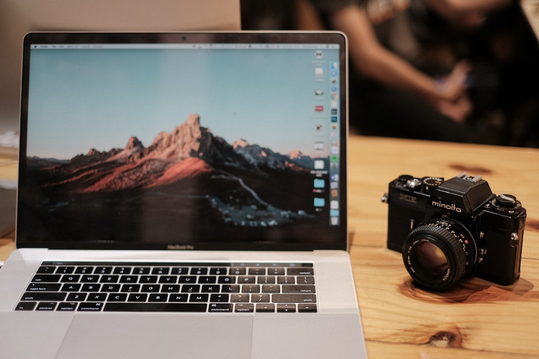 MacBook Pro with touchbar beside black Minolta DSLR camera