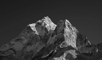 Snow-covered mountain peaks against a dark sky in black and white