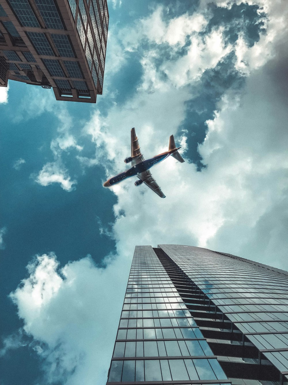 black and white airplane above high-ris ebuildings