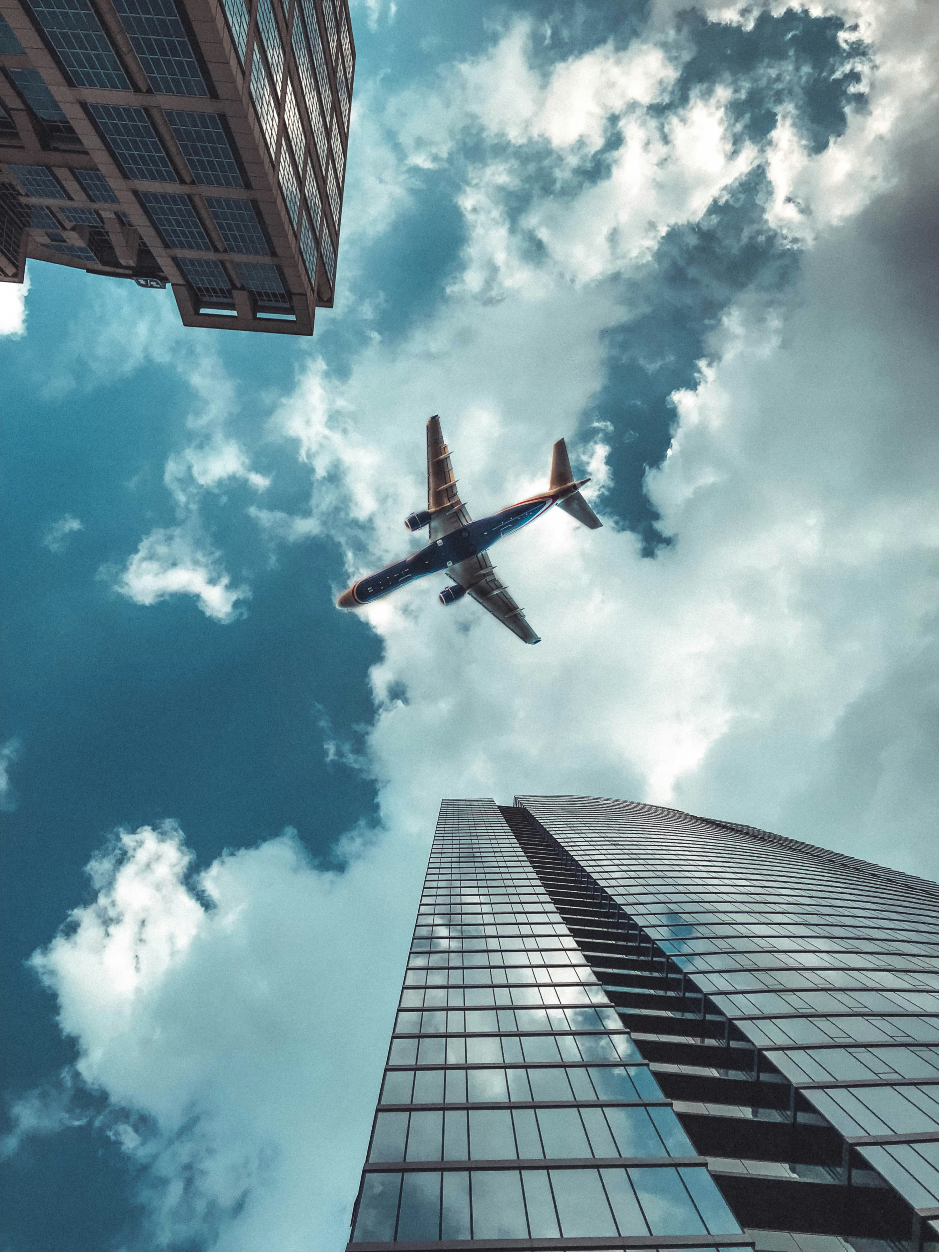 black and white airplane above high-ris ebuildings