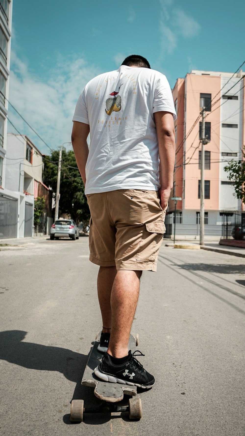 man in white shirt riding on longboard on street during daytime