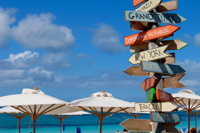 White umbrellas on Grace Bay Beach, Providenciales, Turks and Caicos, with a signpost pointing to Grand Turk and North Caicos