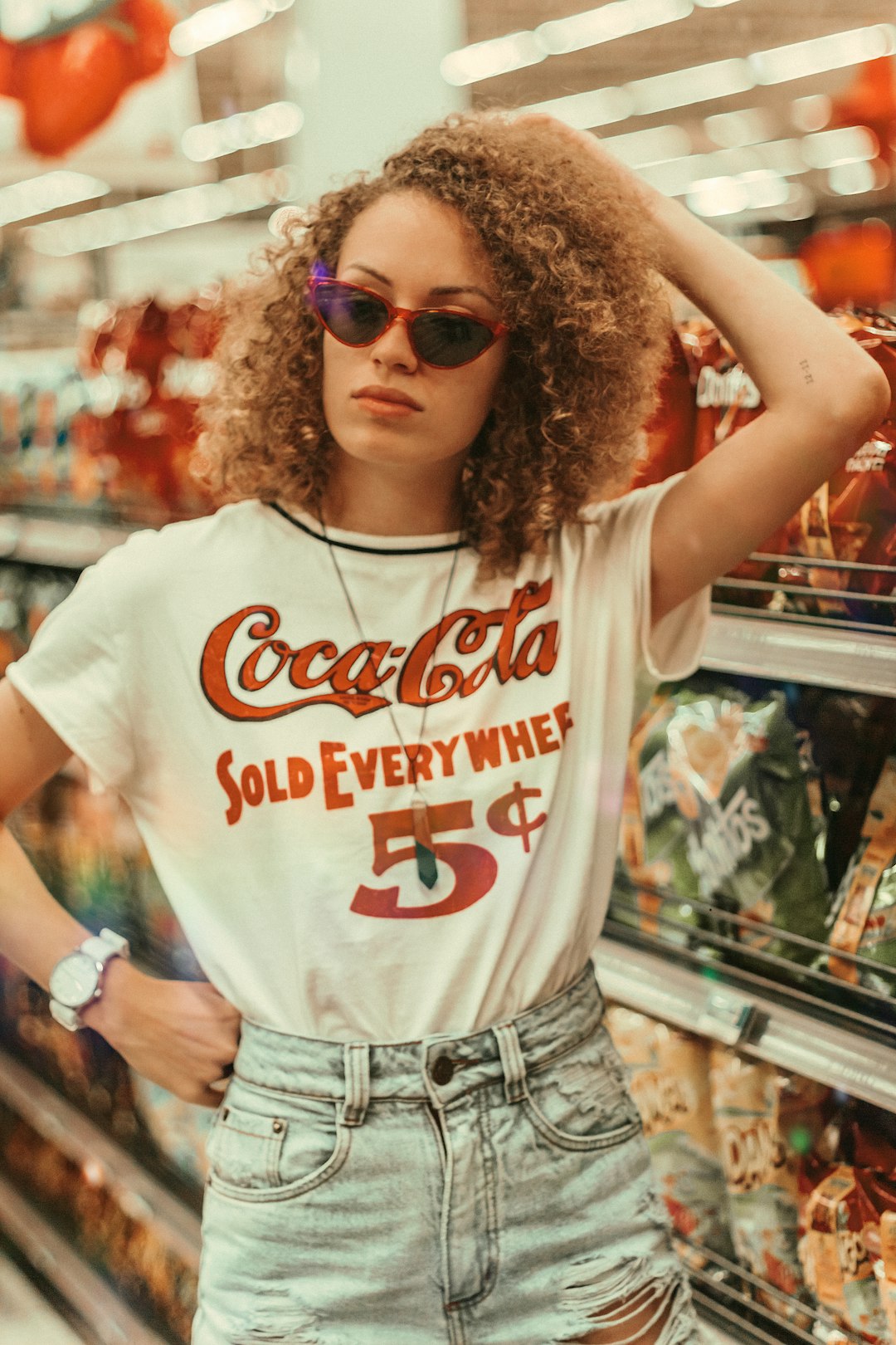 woman wearing white Coca-Cola shirt and blue distressed denim bottoms