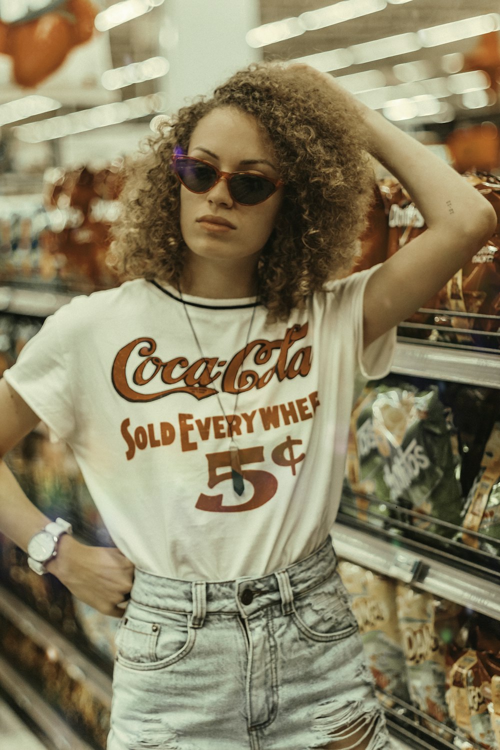 woman wearing white Coca-Cola shirt and blue distressed denim bottoms