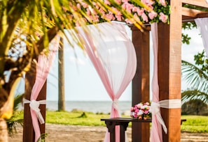 brown wooden gazebo with pink curtain