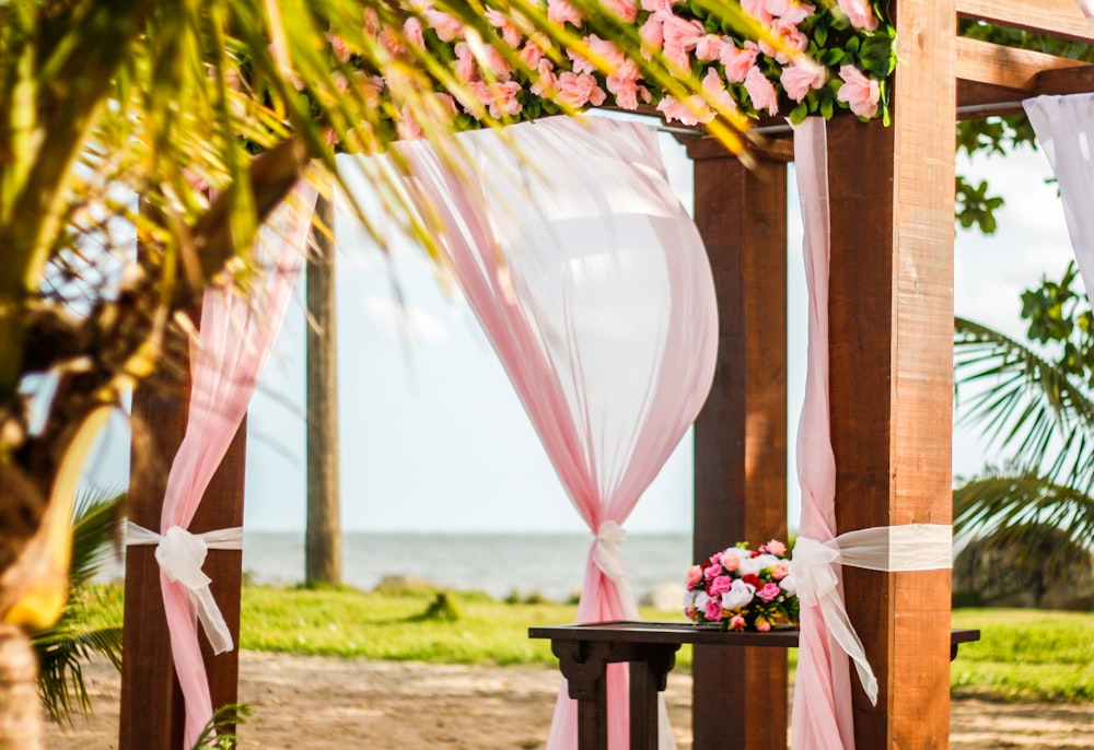 Cenador de madera marrón con cortina rosa