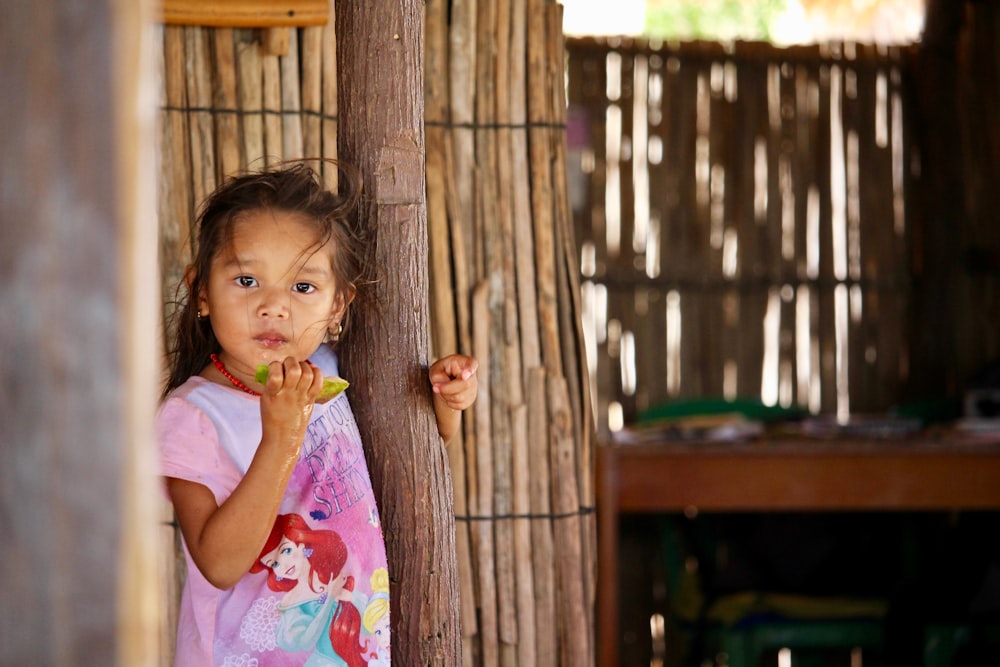 shallow focus photo of girl leaning on wooden post