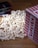 A pile of popcorn spilled out from a red and white striped container, with several DVD cases laying nearby on a wooden surface.