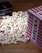 A pile of popcorn spilled out from a red and white striped container, with several DVD cases laying nearby on a wooden surface.