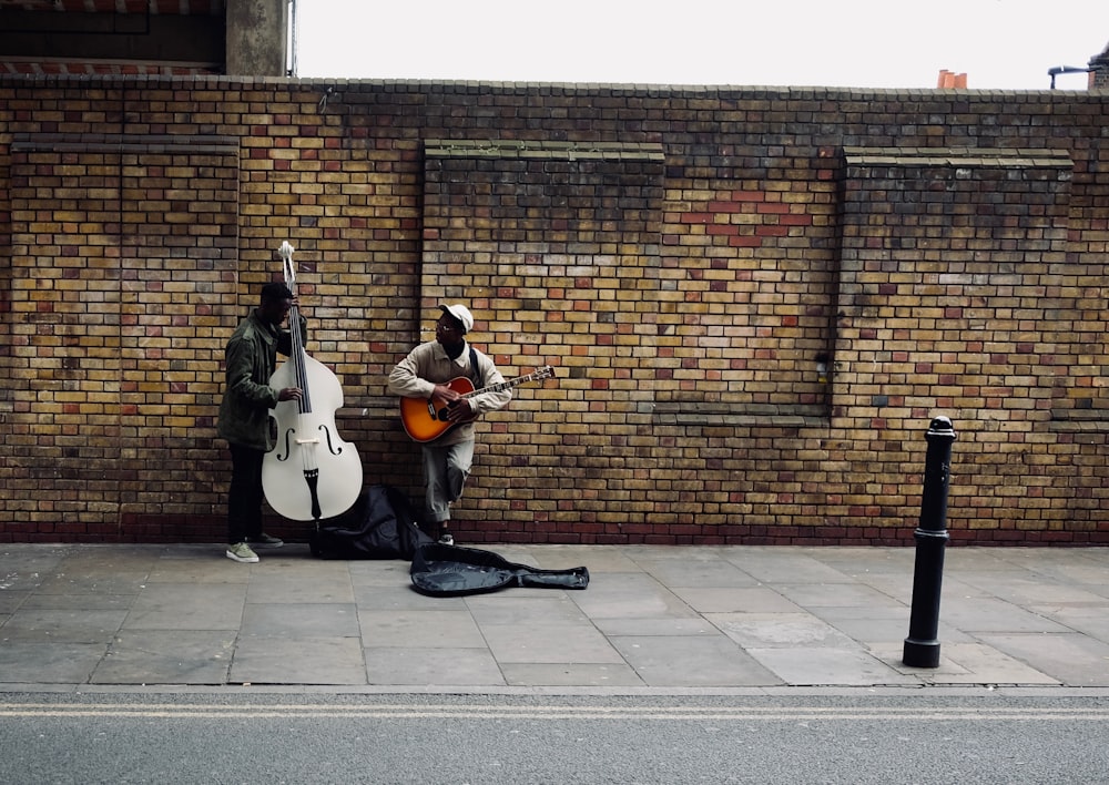 two men playing string instruments beside road