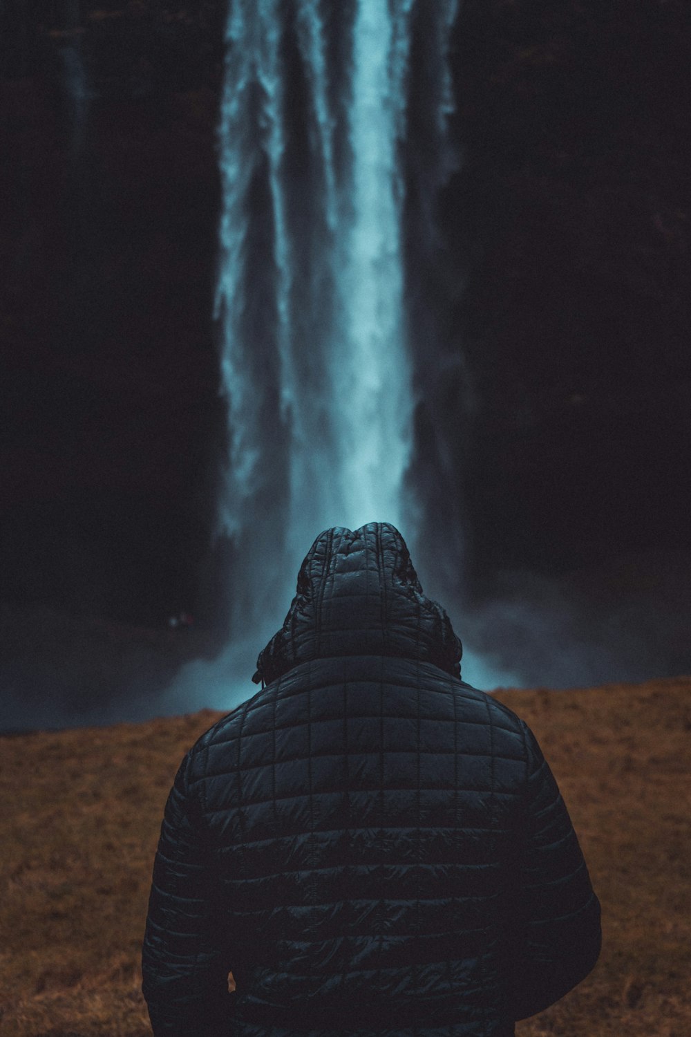 Person, die eine Jacke trägt und auf die Wasserfälle blickt