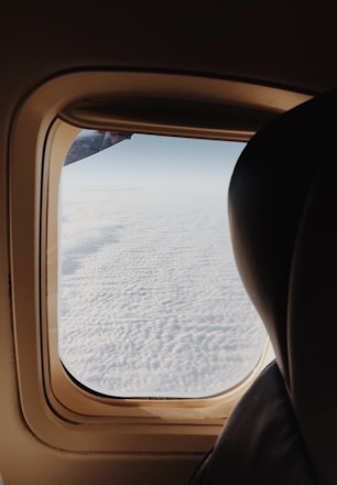A cozy airplane seat with a window view showcasing clouds outside.