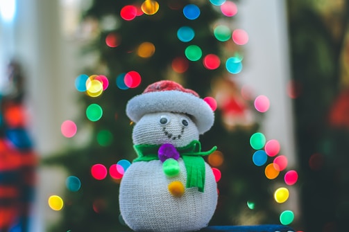 Close-up of a soft knit scarf adorned with tiny embroidered Christmas trees and twinkling lights.