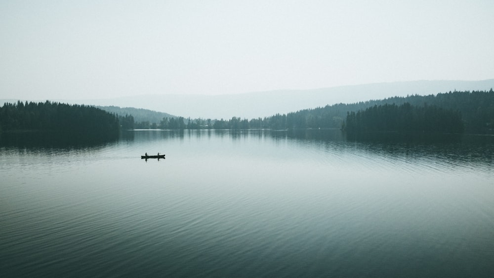 boat on body of water under white sky