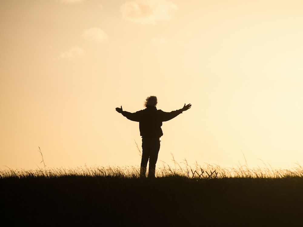 silhouette di persona che allarga le mani