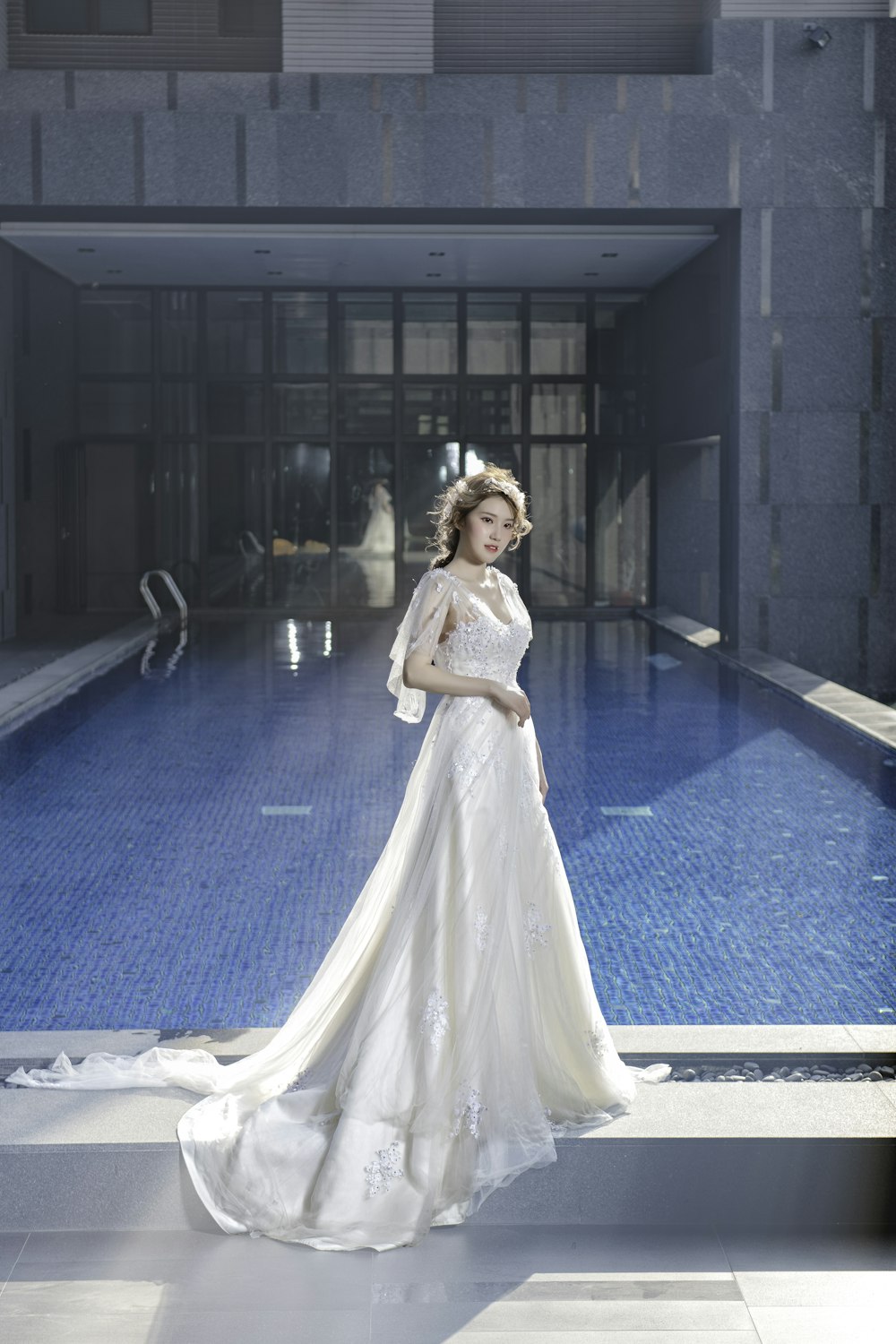 woman in white dress standing near swimming pool during daytime