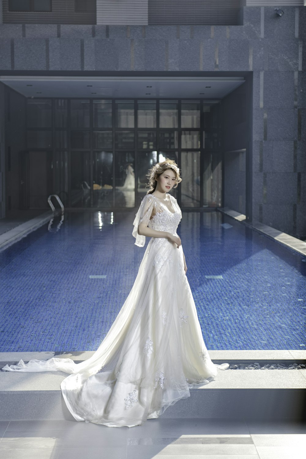 femme en robe blanche debout près de la piscine pendant la journée
