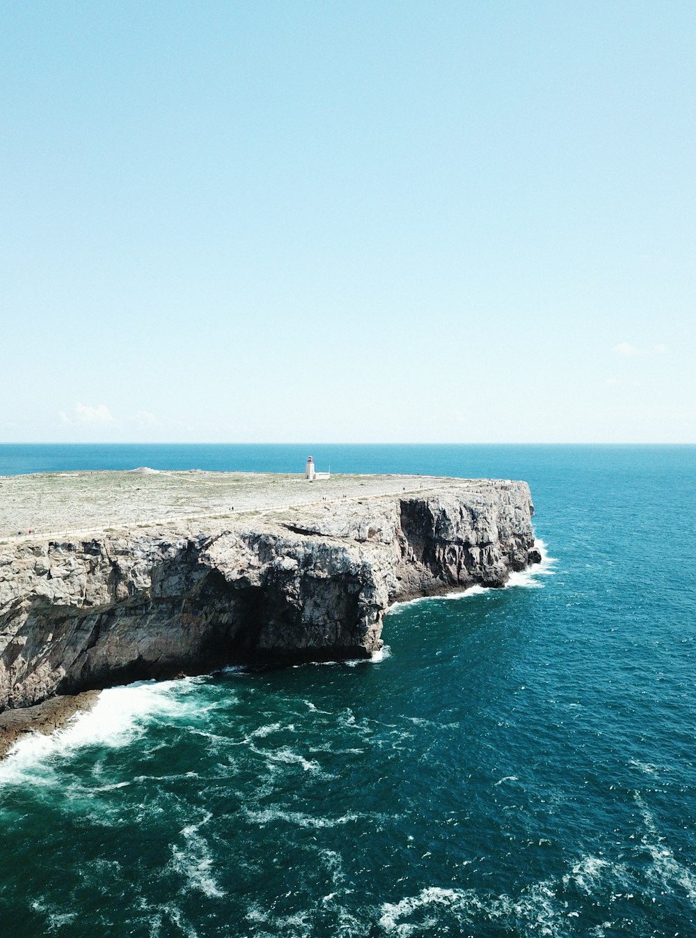 person standing on rock formation cliff beside sea