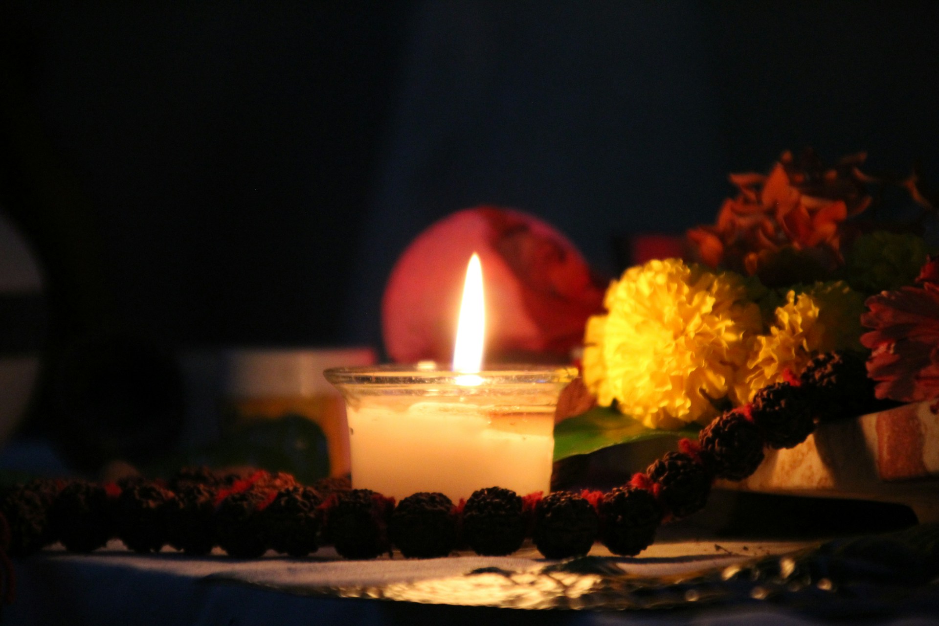 A glowing candle surrounded by sacred herbs and spiritual symbols, casting a warm light.