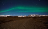 A wide shot of a rugged Icelandic mountain under a vibrant aurora borealis