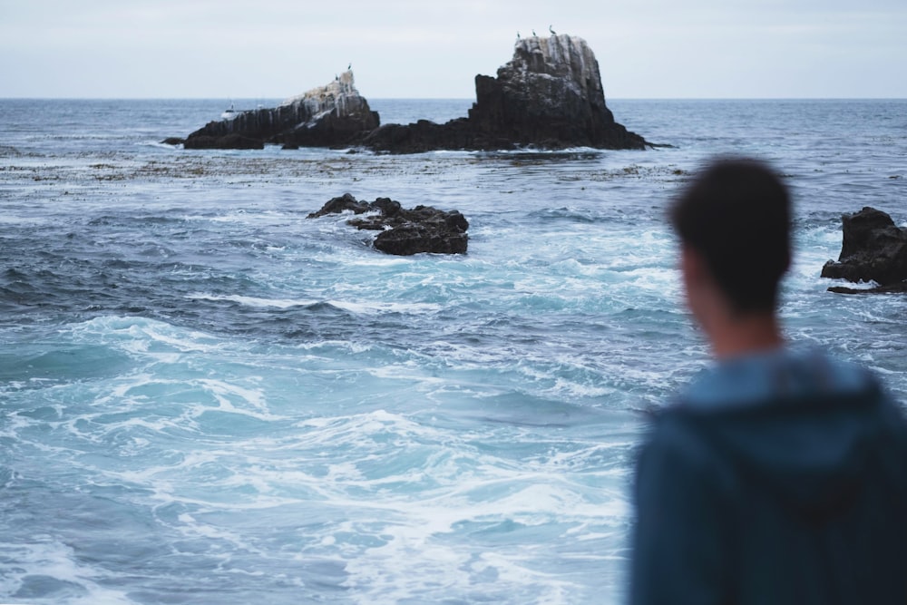 tilt-shift photography of man in front of seashore