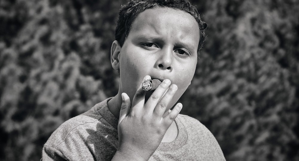 grayscale photography of boy smoking tobacco