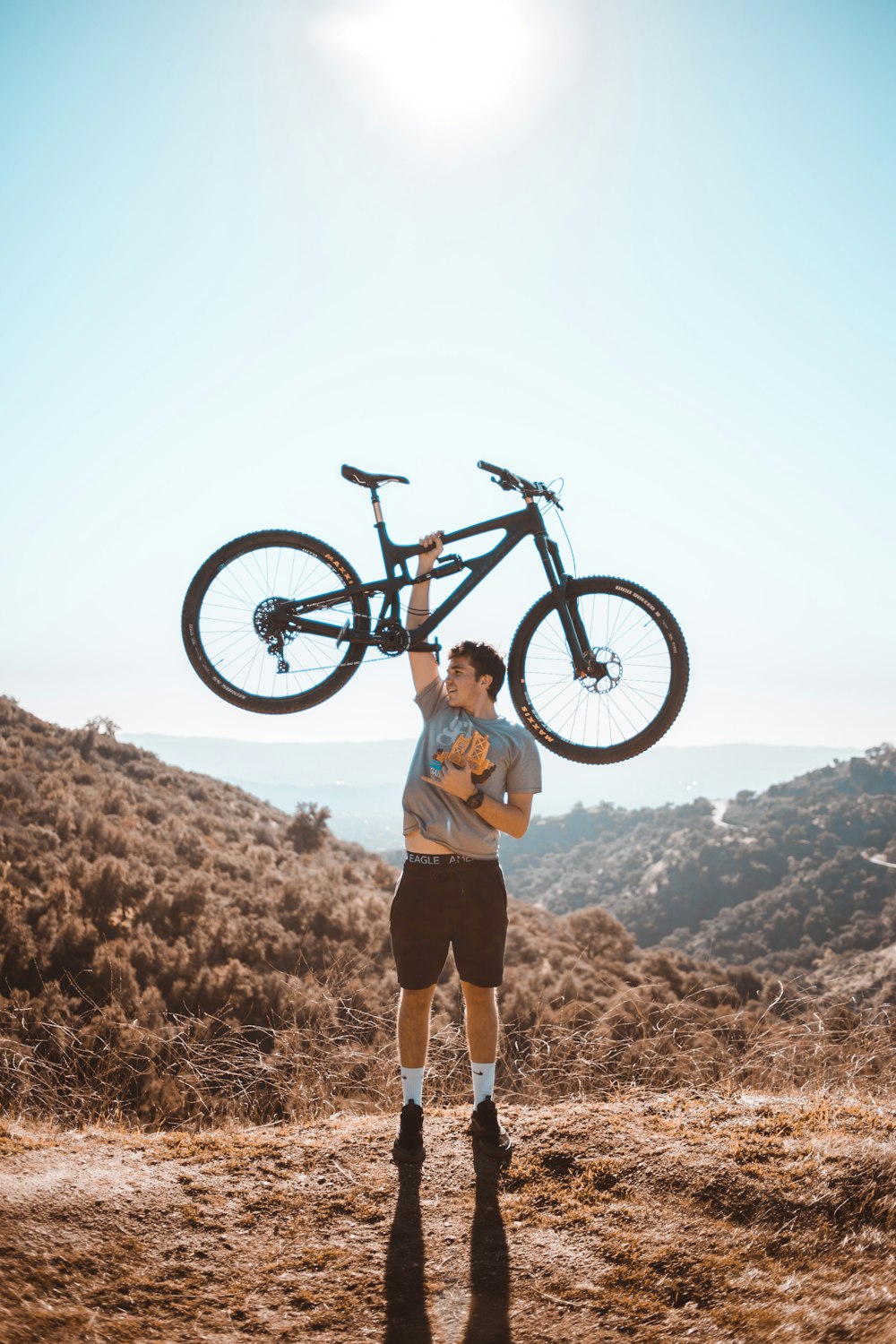 selective focus photography of man lifting full-suspension mountain bike with right hand during daytime