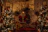 A cozy living room scene with Santa Brent laughing warmly with a family gathered around, twinkling lights softly glowing in the background.