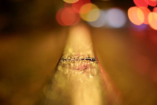A metal rail extends into the distance, with a bokeh effect of colorful lights in the background. The surface of the rail is textured and weathered.